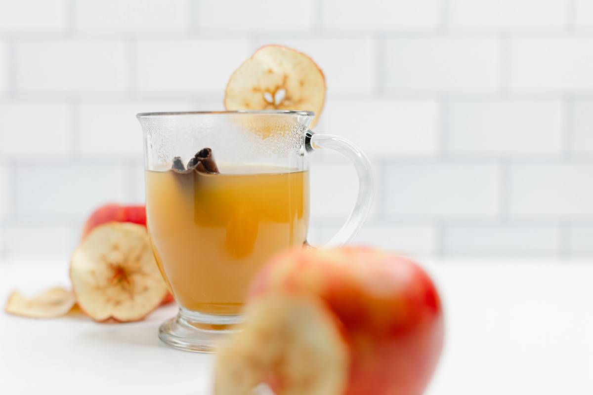 Hot Apple Cider with a cinnamon stick in a clear mug.