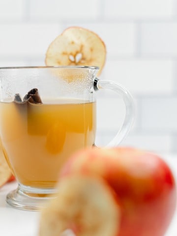 Hot Apple Cider with a cinnamon stick in a clear mug.