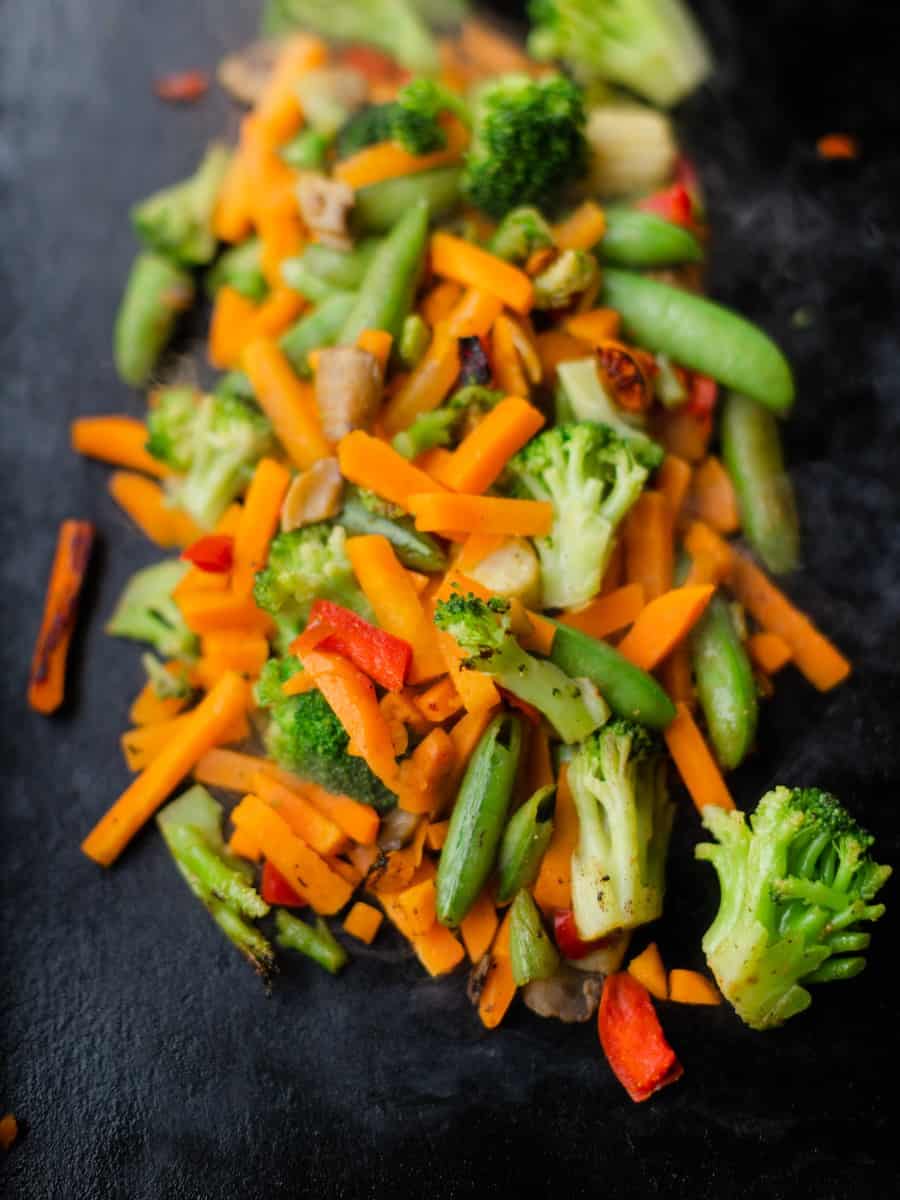An Assortment of Chopped Vegetables on a Blackstone Griddle (Carrots, Broccoli, Snap Peas, Peppers, and Mushrooms).