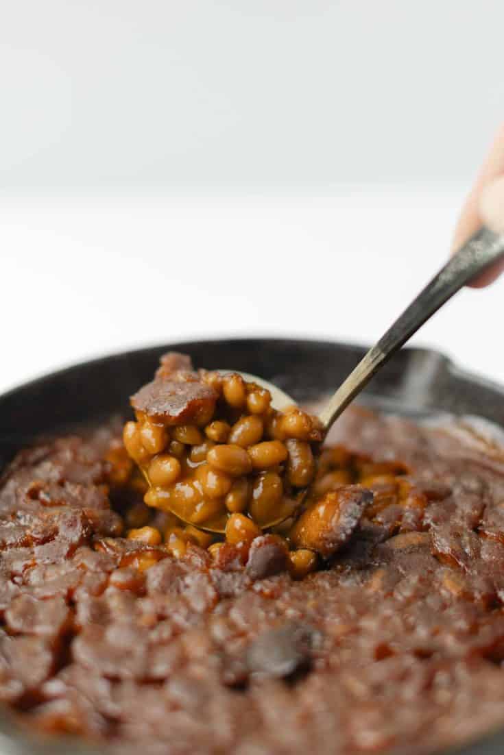 Smoked Baked Beans in a Cast Iron Pan with a ladle scoop full.