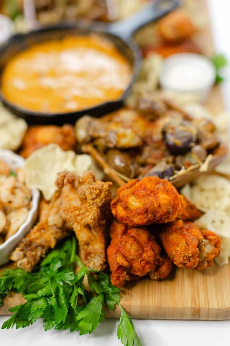 Snacks Charcuterie Board: Assortment of Chicken Wings, Queso Dip, Smashed Potatoes, and Garlic Butter Shrimp.