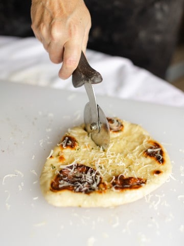 Using a pizza cutter to cut Naan Bread Garlic Recipe