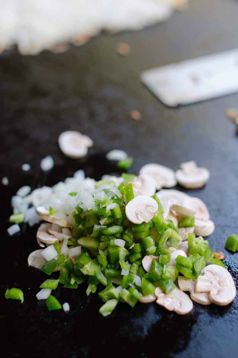 Fresh Diced Onions, Diced Peppers, and Sliced Mushrooms on a Griddle