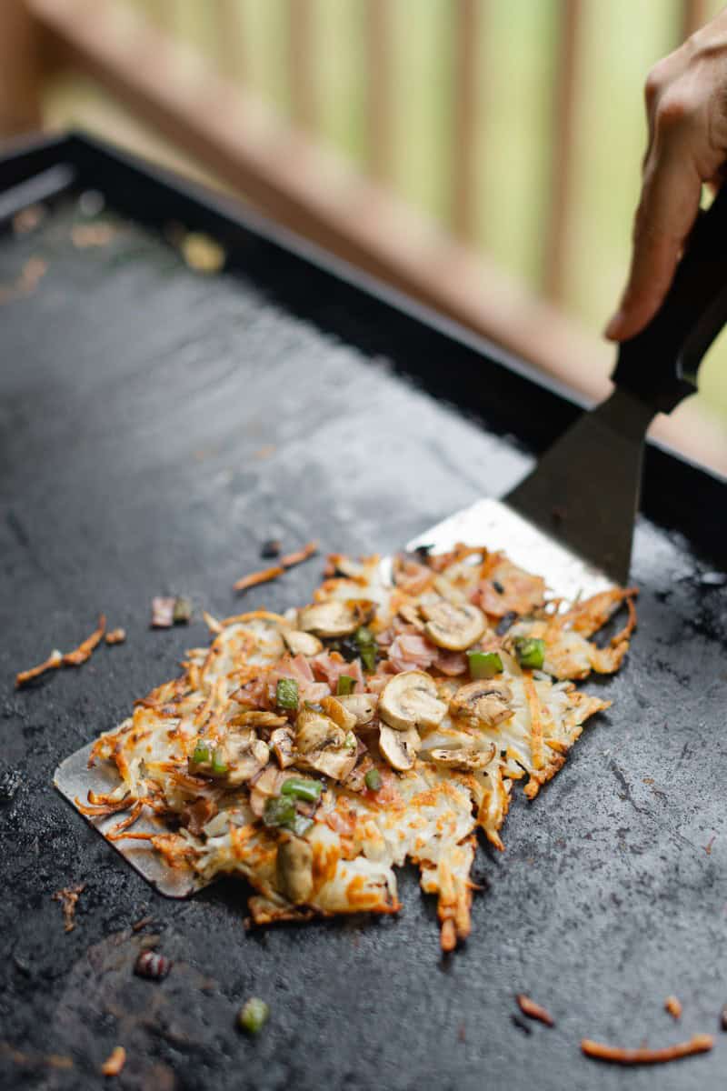 Scooping up Loaded Griddle Hash Browns with a Griddle Spatula