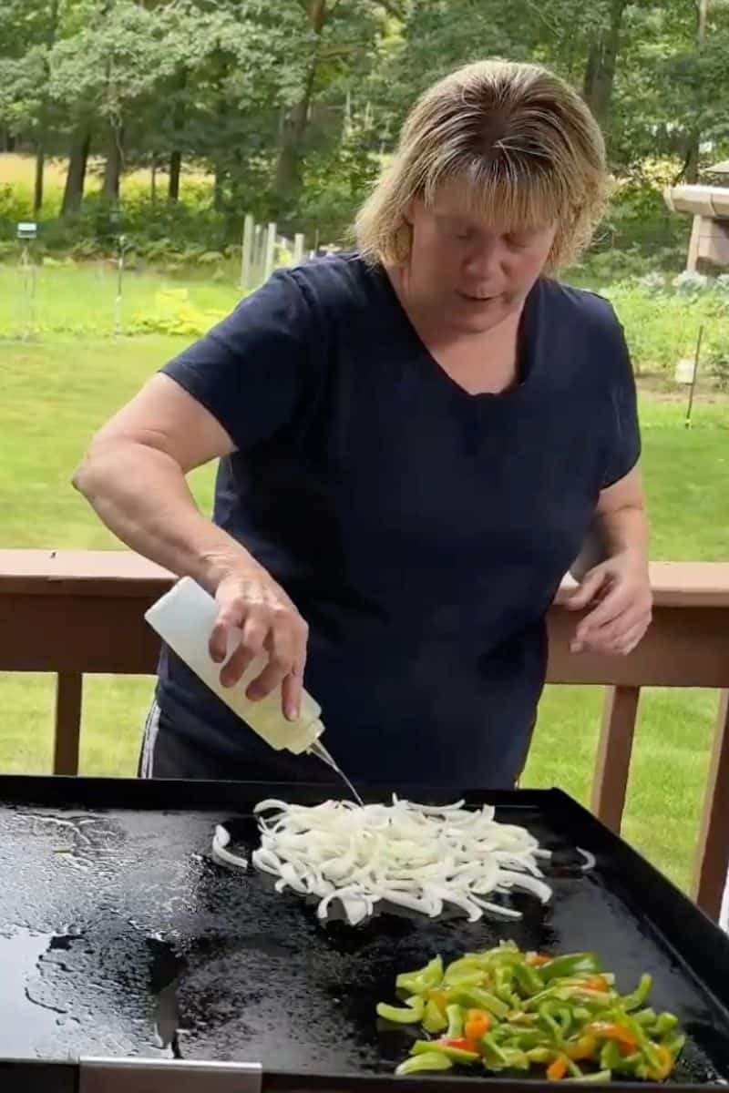 Chef Sherry Ronning Squirting Oil onto Food Cooking on a Blackstone Griddle