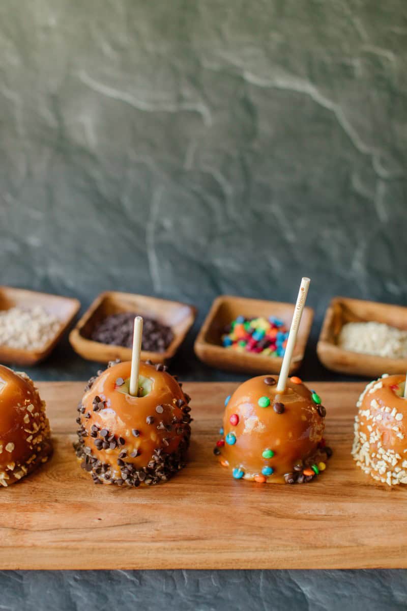 An Assortment of Professional Homemade Caramel Apples displayed on a Wooden Board
