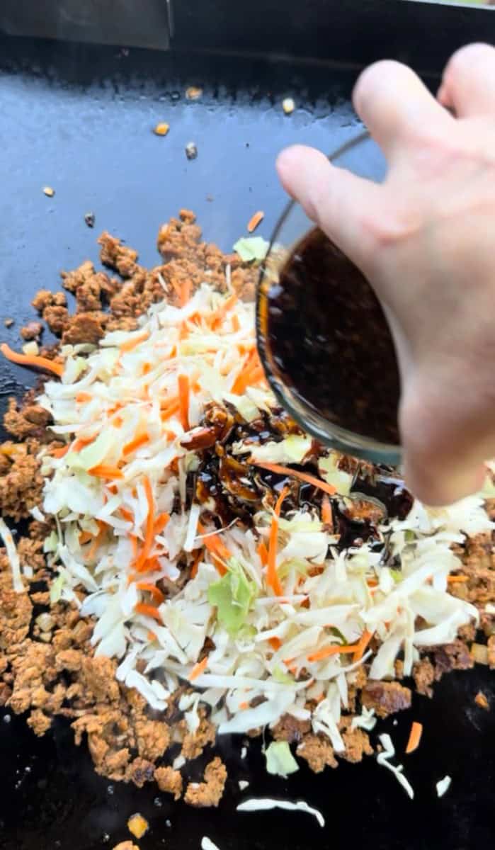 Pouring Egg Roll in a Bowl Sauce overtop Coleslaw and Meat Mixture
