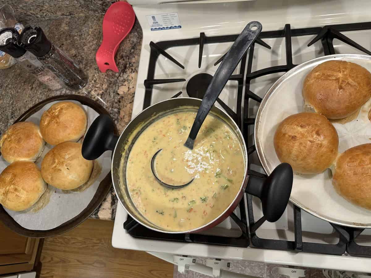 A Pot of Broccoli Cheese Soup surrounded by several Air Fryer Bread Bowls