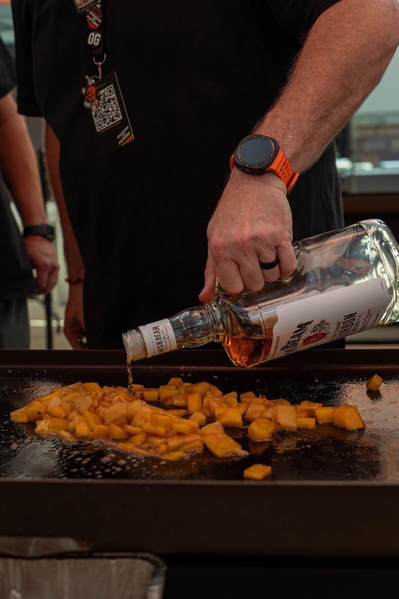 Pouring Alcohol over Fruit Cooking on a Blackstone Griddle