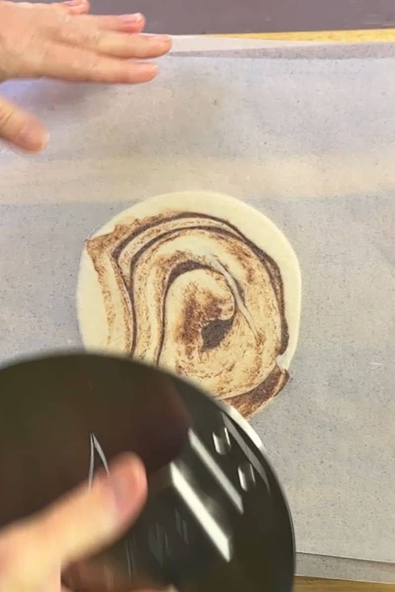 Smashing Cinnamon Rolls between 2 pieces of wax paper