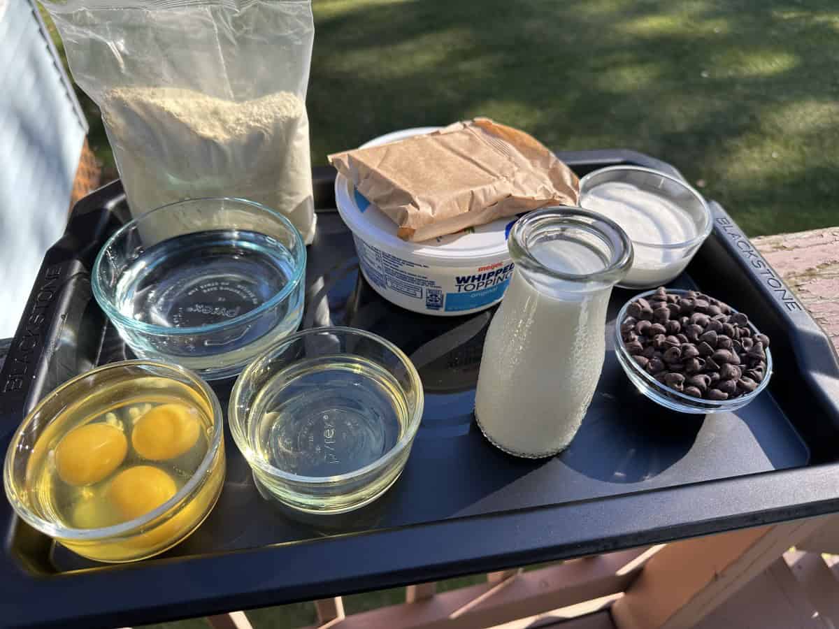 Boston Cream Pie Ingredients: yellow cake mix, eggs, water, oil, milk, pudding mix, Cool Whip, heavy whipping cream, chocolate chips.