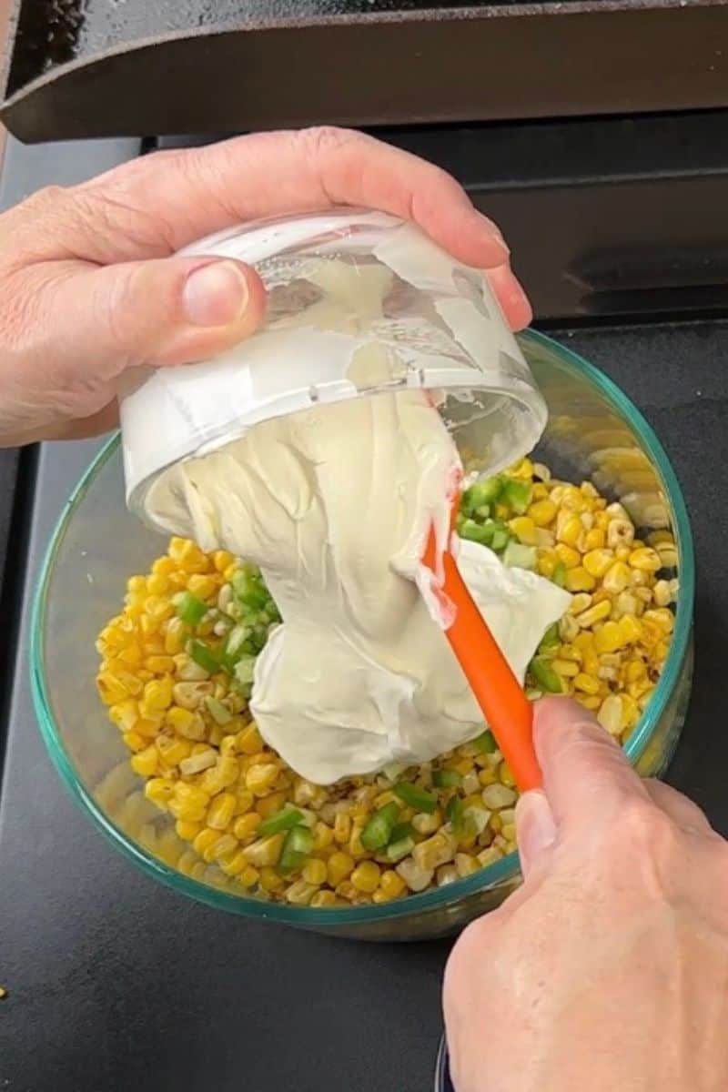 Pouring Sour Cream to fried corn and jalapenos